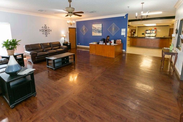 A spacious and well-lit reception area with a wooden desk, a comfortable sofa, and elegant decor.
