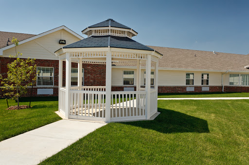 A charming white gazebo nestled in a green lawn, surrounded by a clear blue sky.