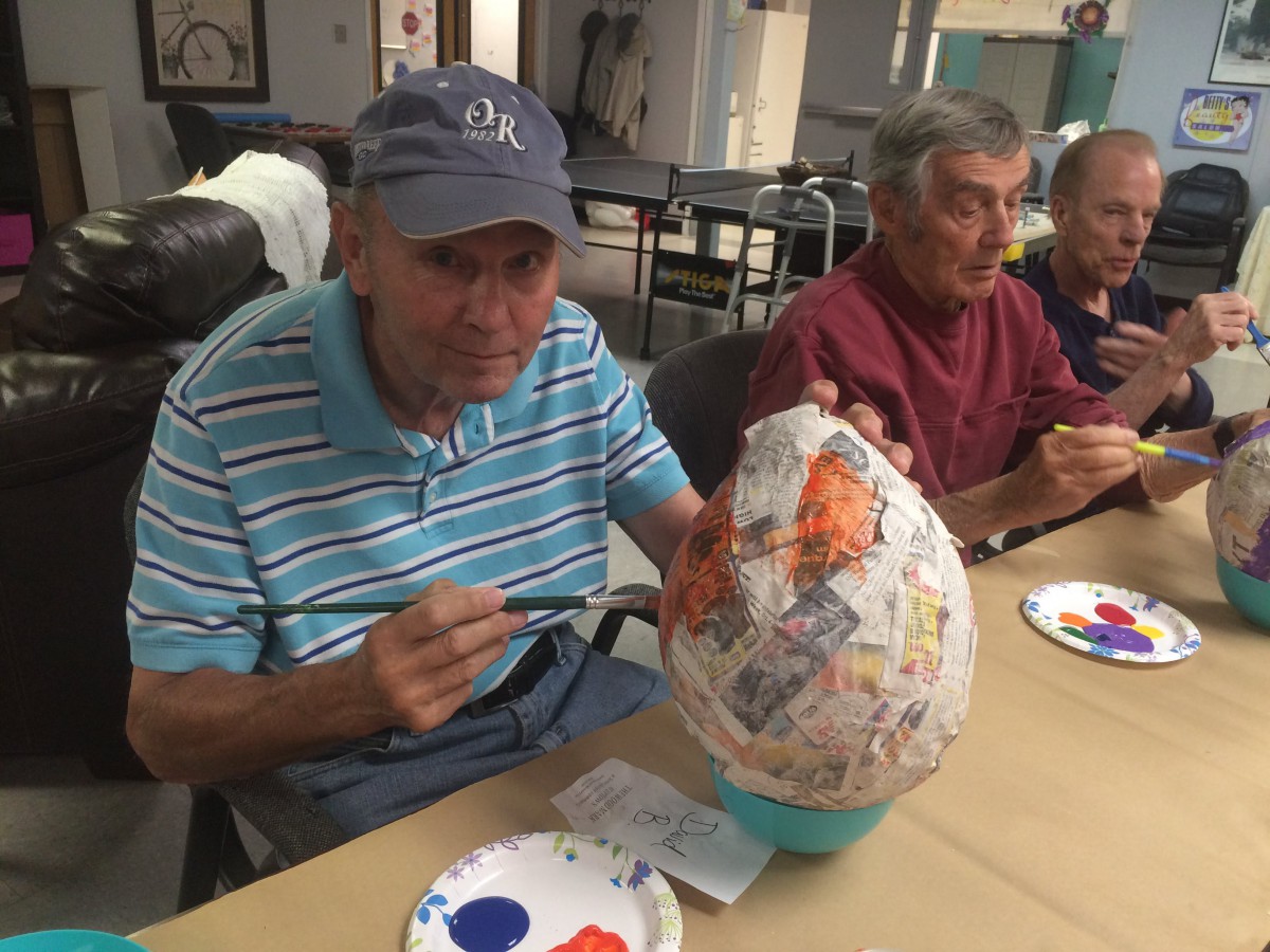 Elderly individuals engaging in a painting and crafting activity.