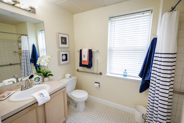 A well-lit and neatly organized bathroom featuring a sink, toilet, and towels.