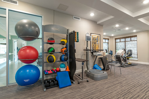 A well-equipped fitness area featuring various exercise equipment including stability balls, medicine balls, and a treadmill.