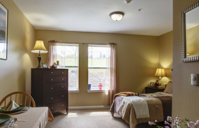 A cozy bedroom with two beds, bedside tables with lamps, and a tall dresser near the window.