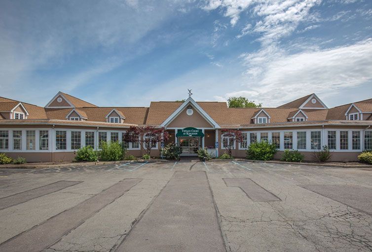 A large building with a triangular roof and multiple windows under a partly cloudy sky.