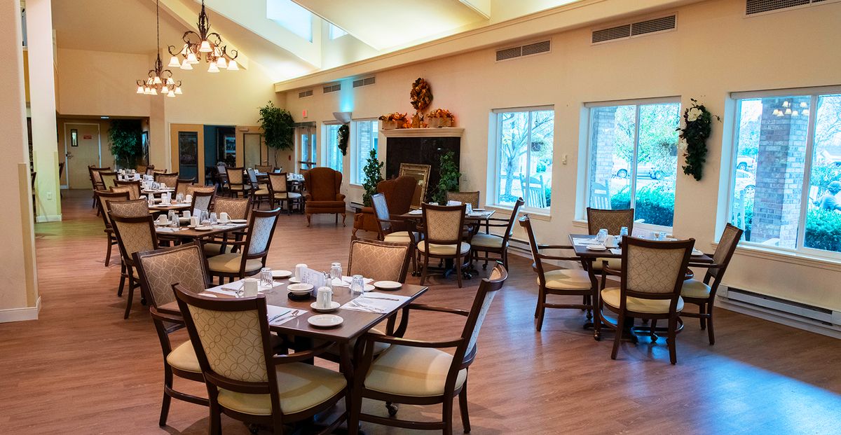 An elegant dining room setup with neatly arranged tables and chairs, featuring large windows and tasteful decor.