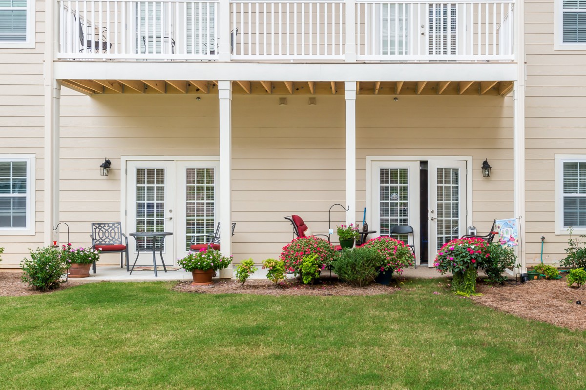 A two-story house with balconies, a well-maintained garden, and patio furniture.