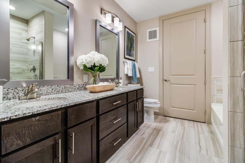 A modern bathroom with a double vanity, granite countertops, and contemporary decor.