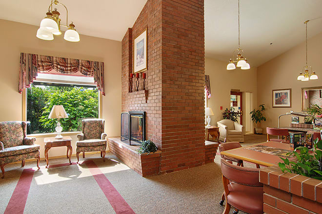 A cozy living room featuring a brick fireplace, traditional furniture, and a dining area.