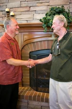 Two men shaking hands in a warm indoor setting.