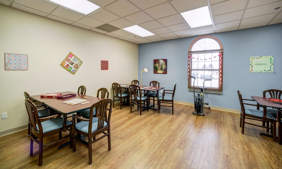 A cozy dining area with tables, chairs, and decorative wall art under bright lighting.