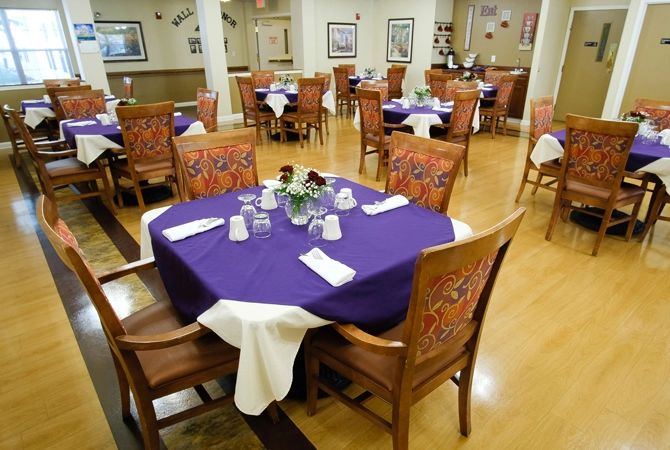 An elegantly set dining area with tables adorned in purple tablecloths and decorative place settings.