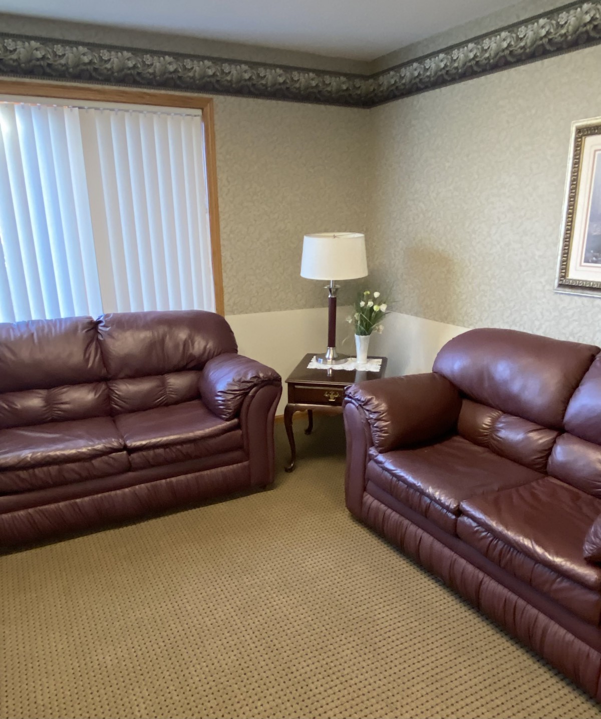 A cozy living room with leather sofas and a small lamp on a table.
