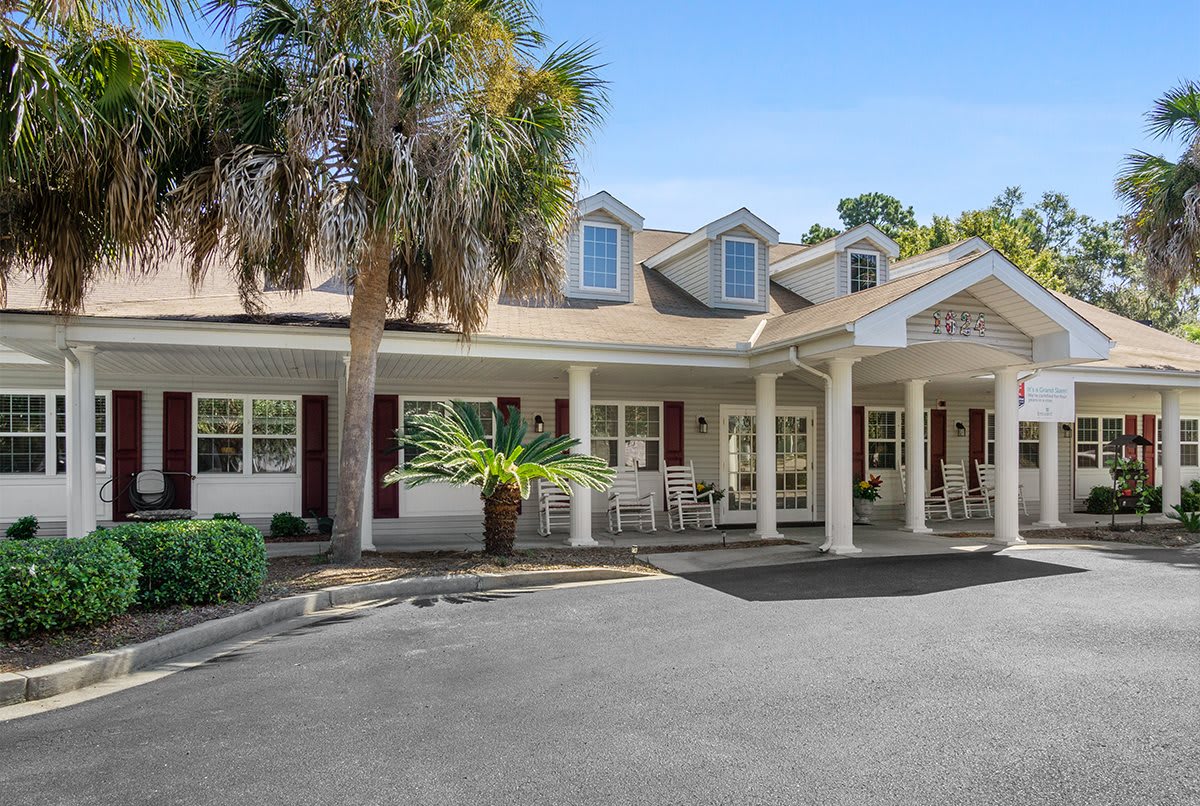A single-story residential building with a porch and palm tree in the front yard.