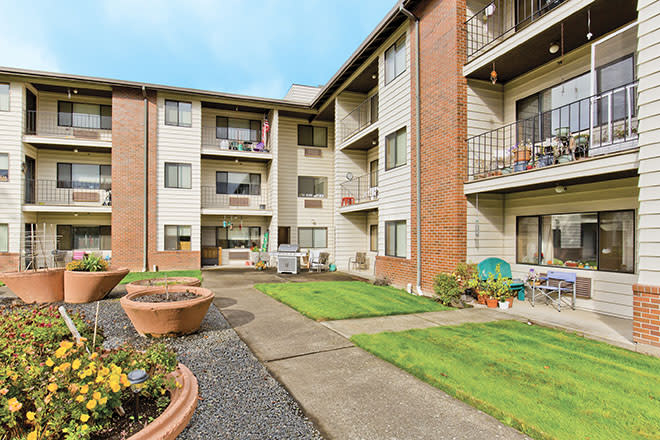 A three-story apartment building with a well-maintained courtyard and balconies.