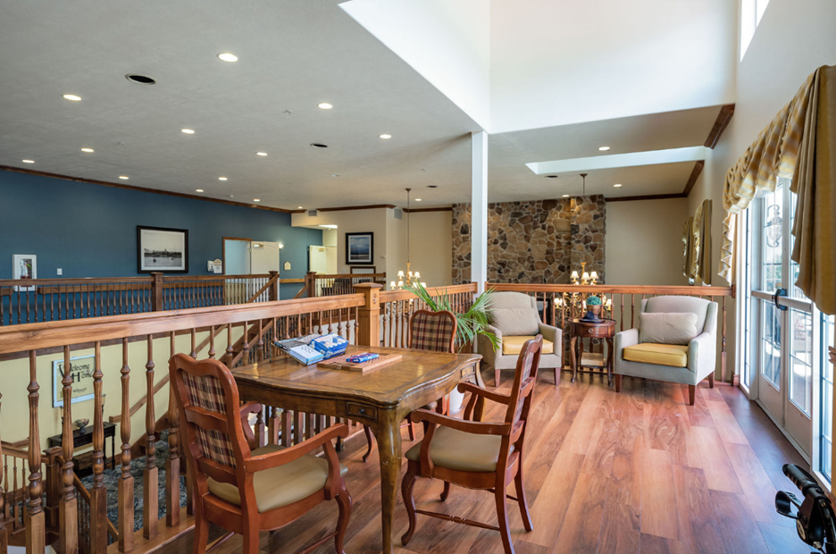 A modern living room with a wooden table and chairs, featuring ample natural light and elegant decor.