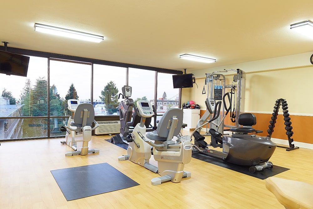 A modern gym with various exercise equipment, including treadmills, stationary bikes, and elliptical machines.