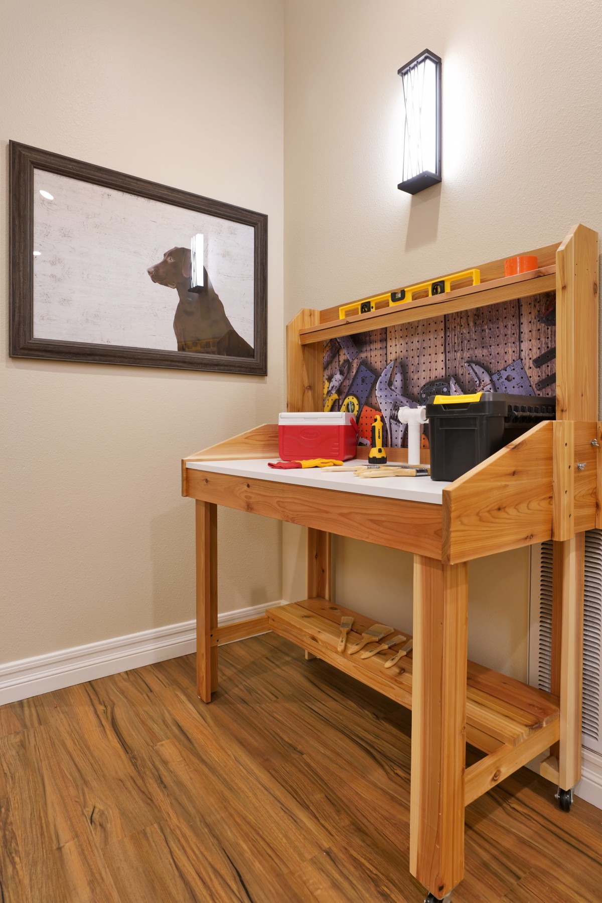 A well-organized home workshop featuring a sturdy wooden workbench equipped with various tools and storage solutions, accentuated by wall art and warm indoor lighting.