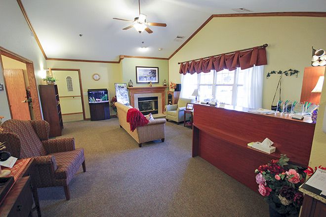 A cozy reception area with seating, a fireplace, and large windows.