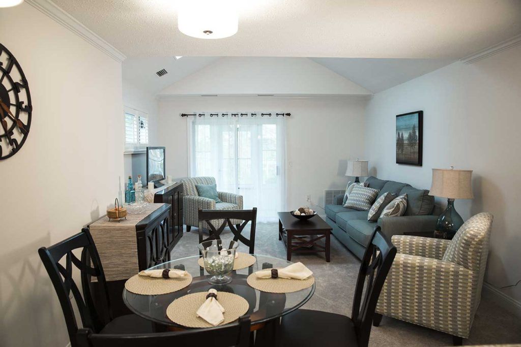 A cozy and modern living room with an adjacent dining area, featuring comfortable furniture and bright lighting.