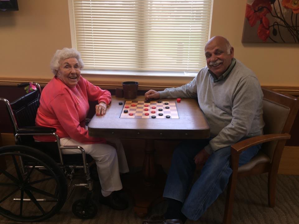 Two seniors enjoying a game of checkers indoors.
