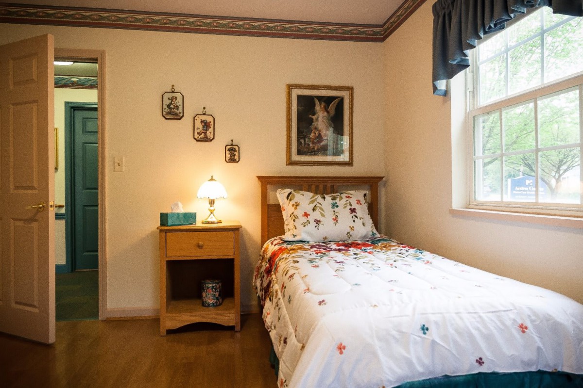 A cozy bedroom with a single bed, bedside table, and wall decorations.