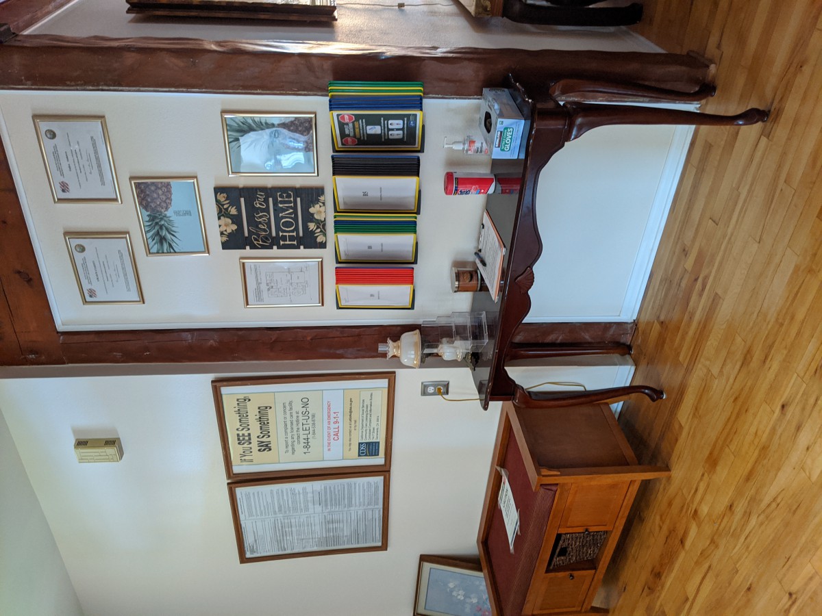 A cozy office space with a wooden desk, books, and framed certificates on the wall.