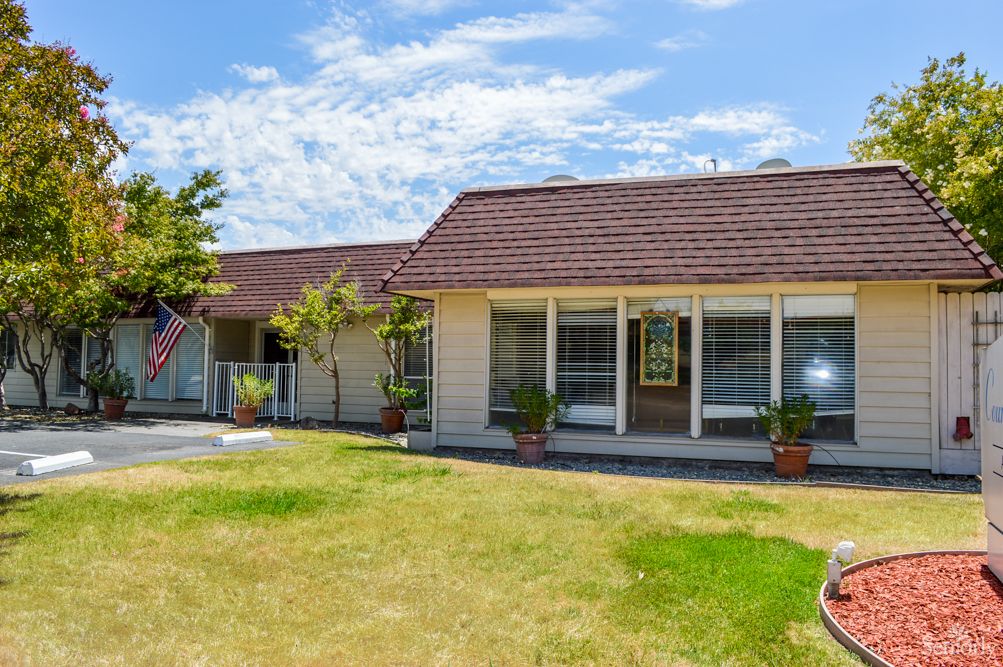 A single-story house with a large lawn and clear blue sky.