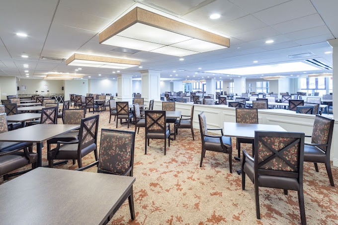 A spacious dining area with modern design, featuring multiple tables and chairs arranged neatly under soft lighting.