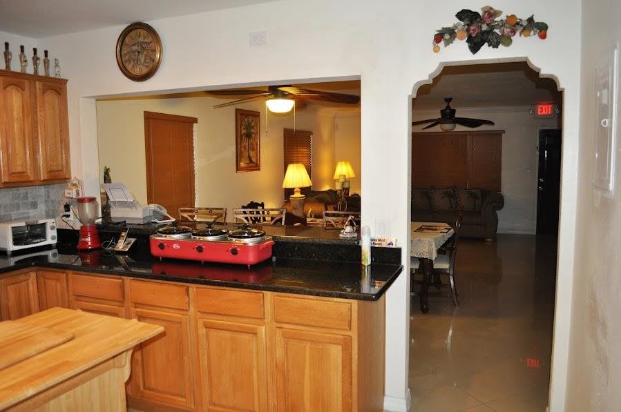 A cozy kitchen with wooden cabinets overlooking a dining and living area.