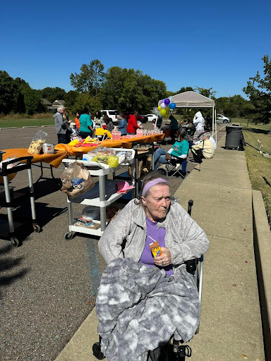 A sunny day at a community event where people gather to participate in food distribution, with a focus on senior citizens enjoying the atmosphere.