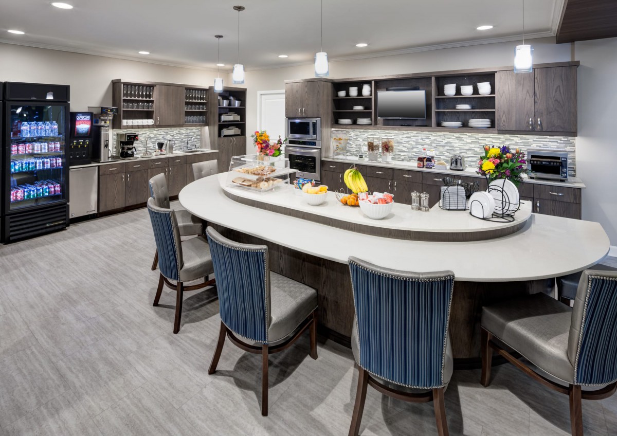 A modern kitchen with a spacious island, equipped with appliances and stylish seating.