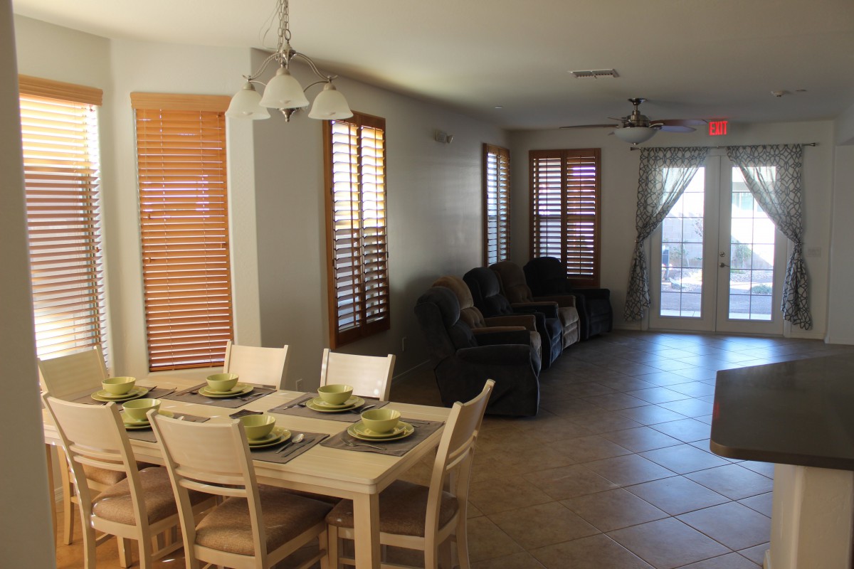 A cozy dining and living area with a wooden dining table, chairs, and a row of comfortable sofas by the windows.