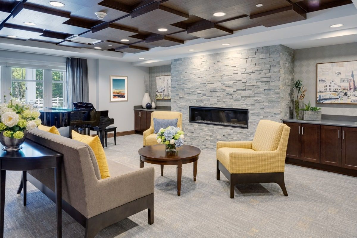 A modern living room with a stone fireplace, featuring yellow and beige seating.