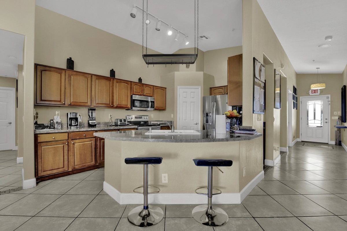 A modern kitchen with wooden cabinets, a central countertop, and sleek bar stools.