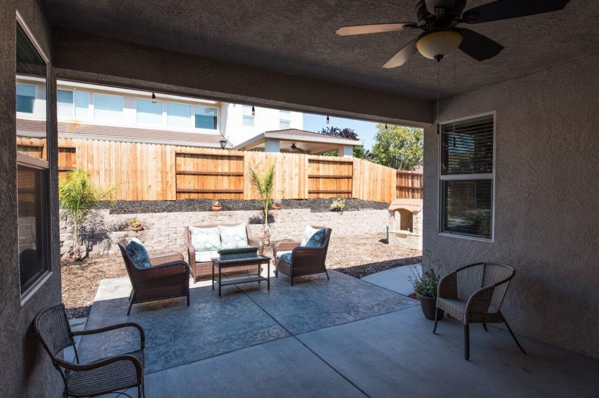 A cozy backyard patio with comfortable seating and a wooden fence.