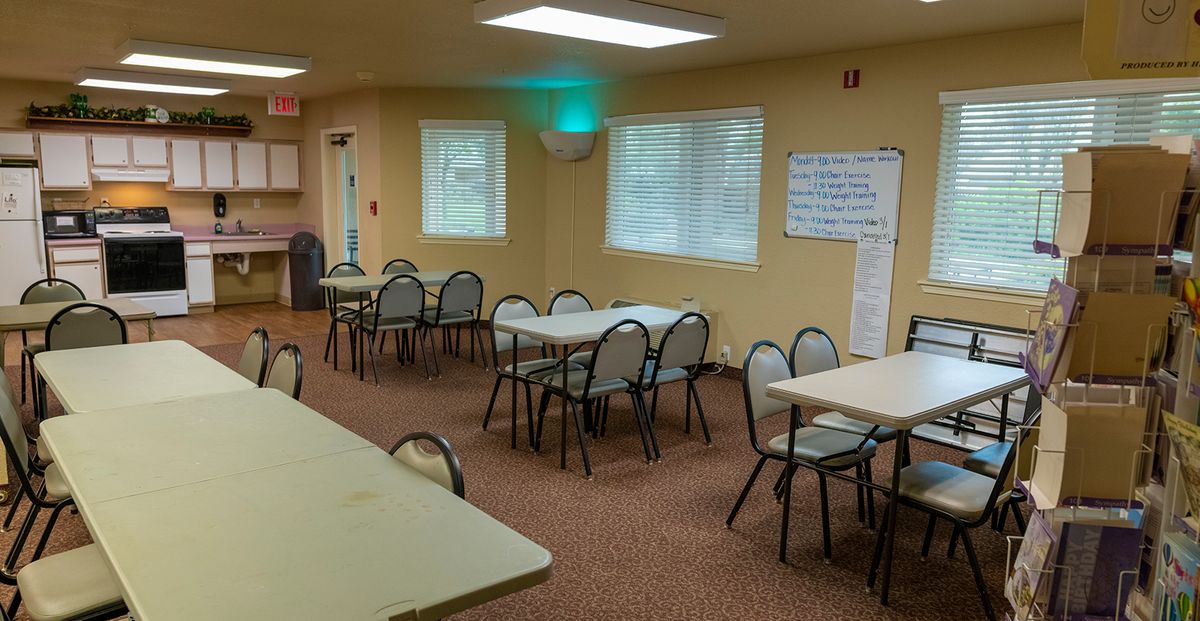 An empty meeting room with tables and chairs arranged for a conference or gathering.