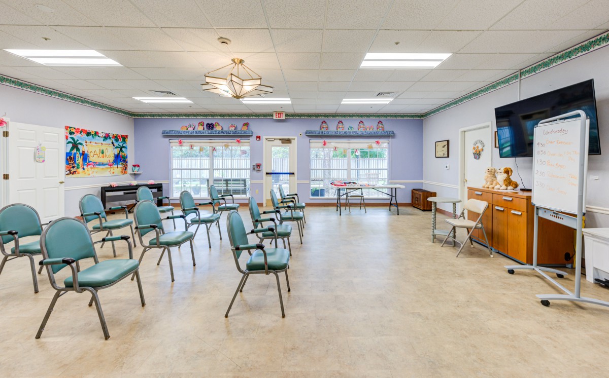 An empty classroom with chairs arranged in rows and a piano against the wall.