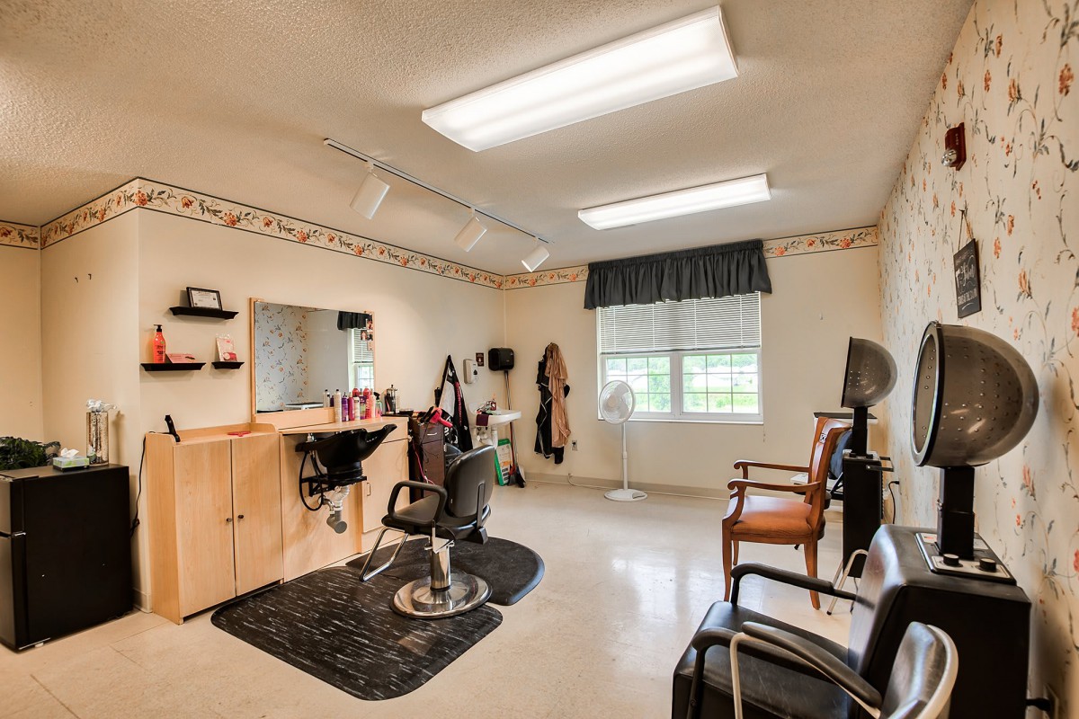 A cozy hair salon with various styling tools and chairs, illuminated by natural light through a window.
