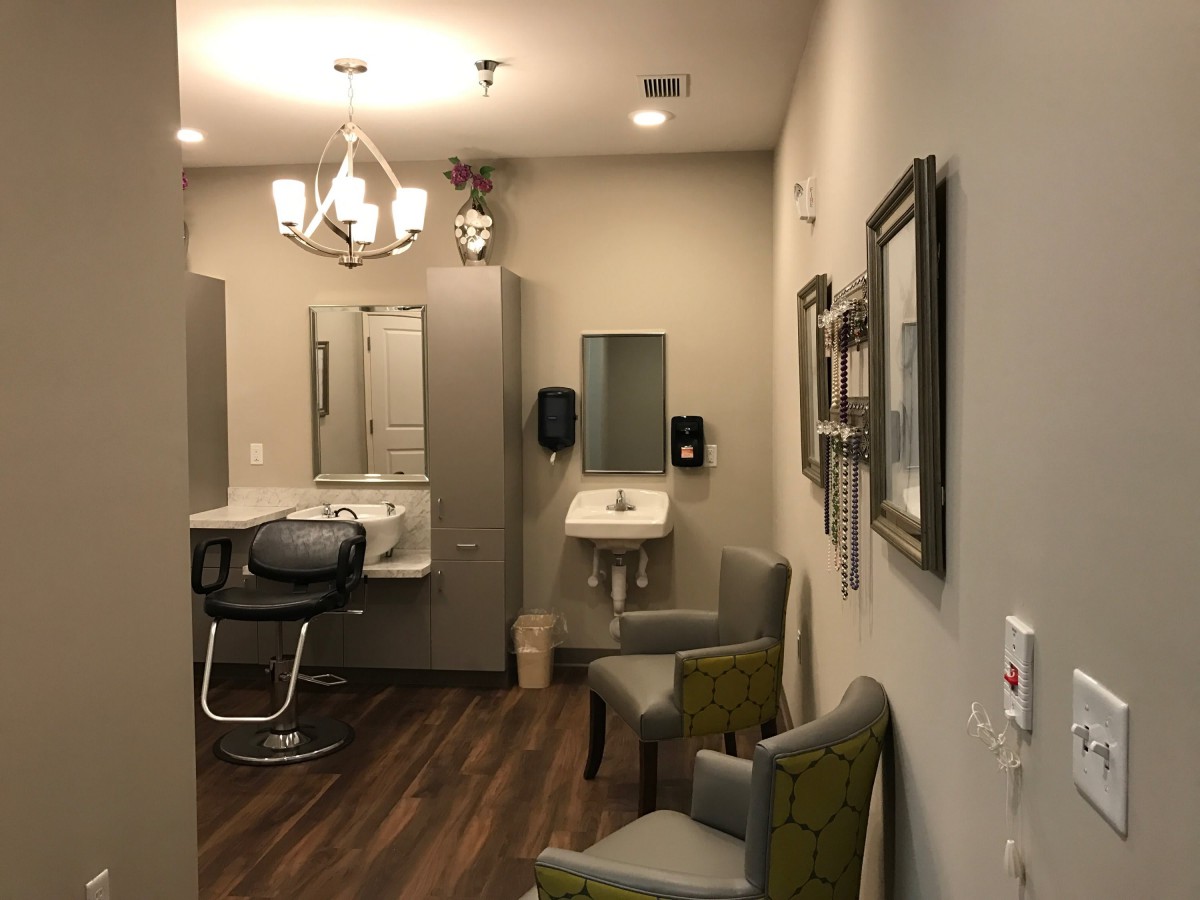 A modern salon interior featuring a makeup station and hair styling chair under elegant lighting.