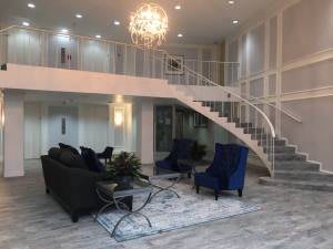 A modern and luxurious living room with elegant furniture, a chandelier, and a sweeping staircase.