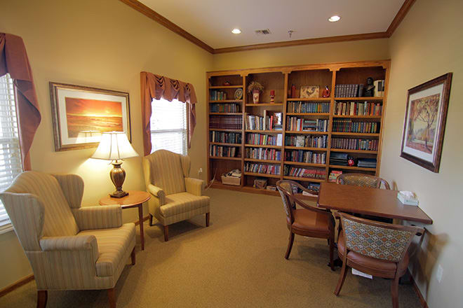 A cozy reading room with bookshelves, armchairs, and a table.