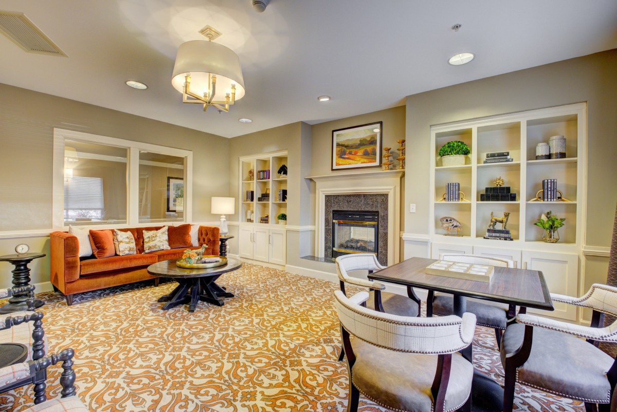 A cozy living room with elegant furniture, a fireplace, and decorative shelving.