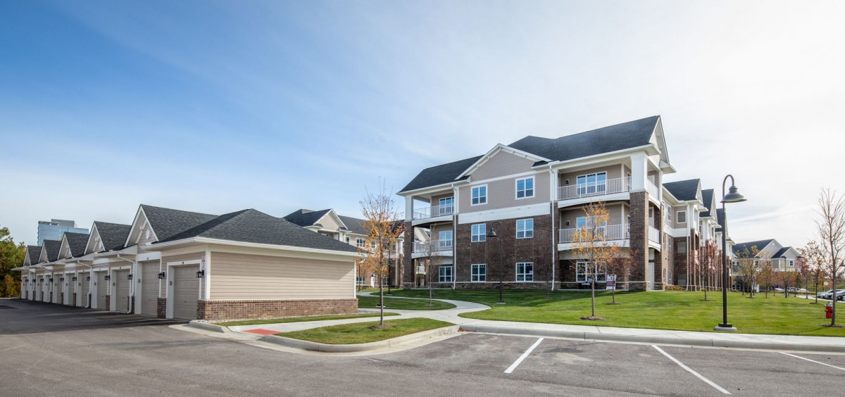 A modern suburban apartment complex with a parking lot and well-maintained surroundings.