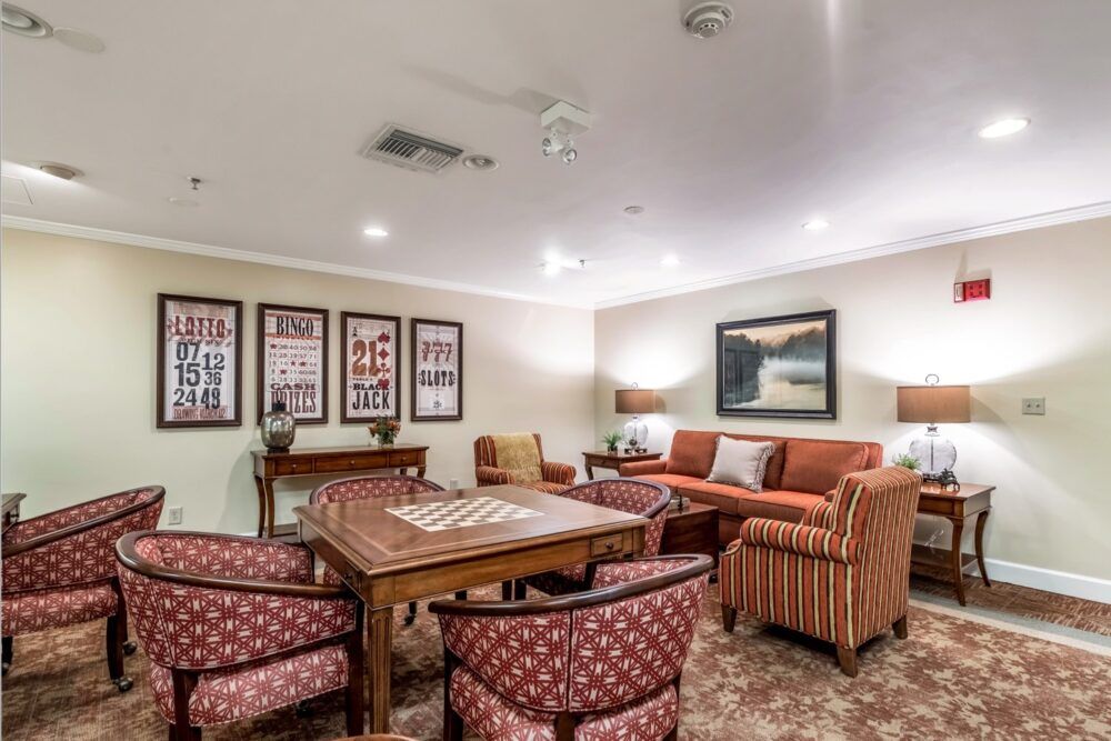 A cozy living room featuring a comfortable seating area with sofas and chairs, a central table, decorative artwork on the walls, and warm lighting.