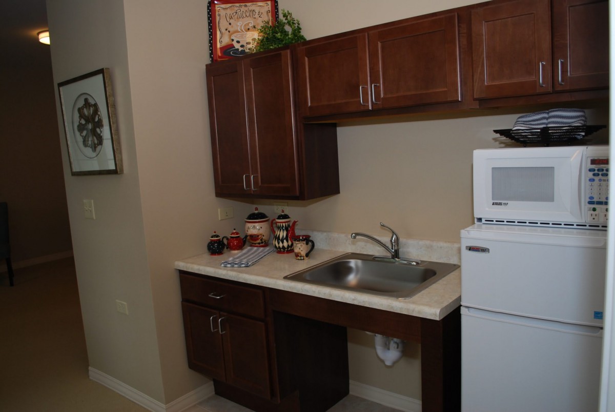 A compact kitchen area with a sink, wooden cabinets, and appliances.