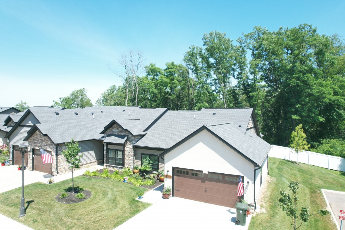 A suburban house with a front yard and garage, surrounded by trees.