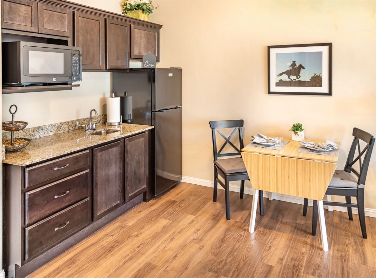 A cozy kitchen with dark wood cabinets, a small dining table, and modern appliances.