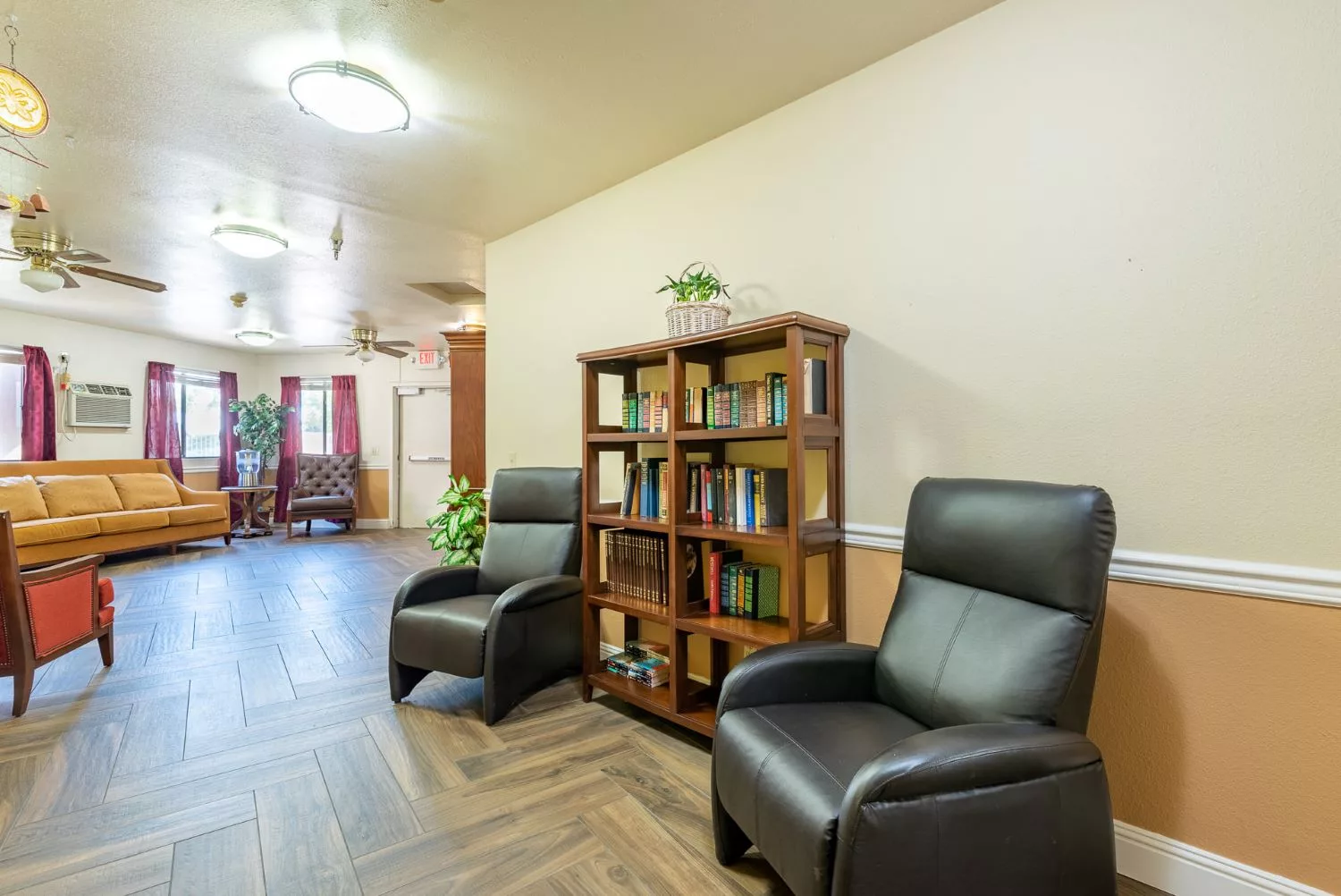 A cozy living area with two black chairs and a wooden bookshelf.