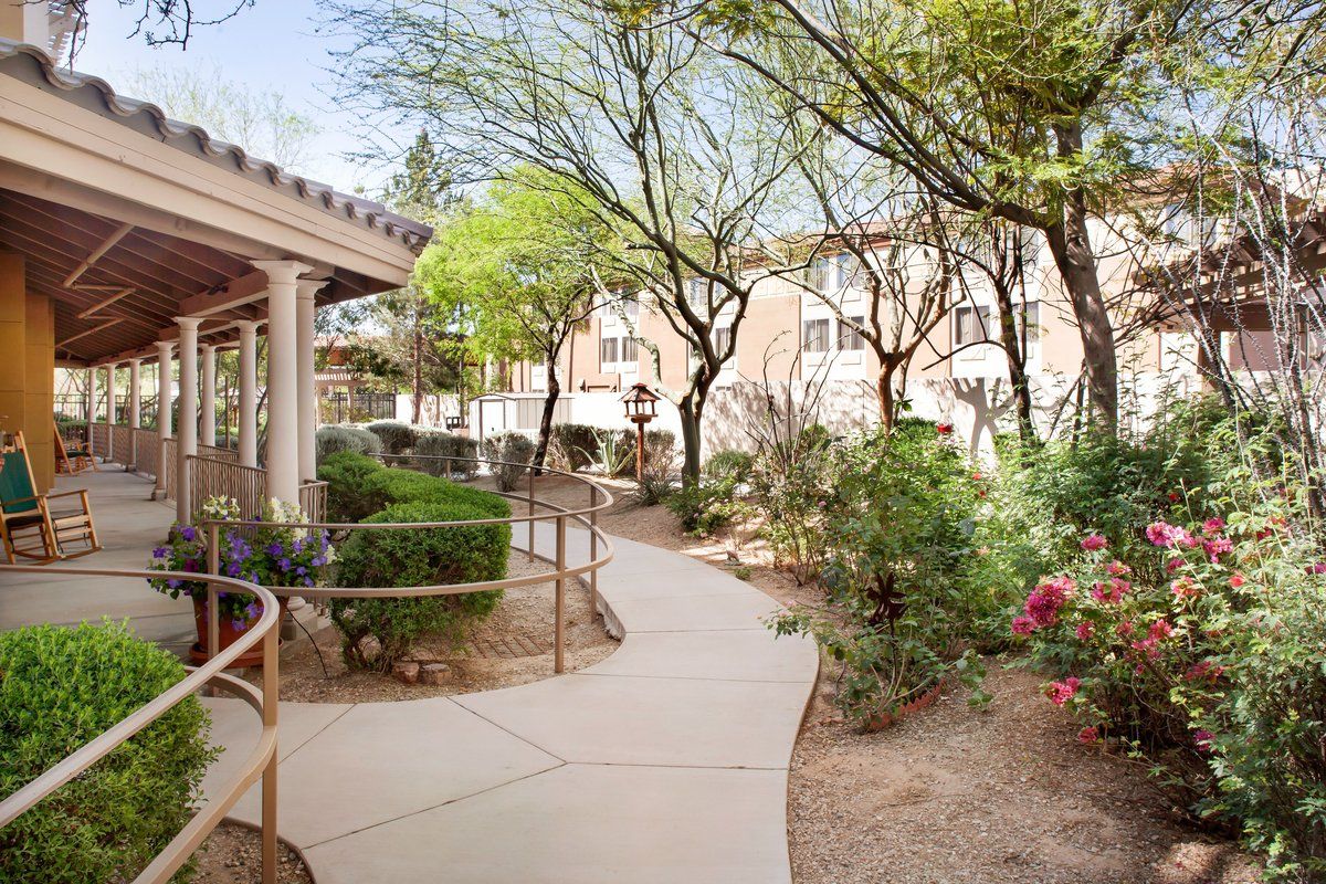 A serene garden walkway surrounded by lush greenery leading to a building.