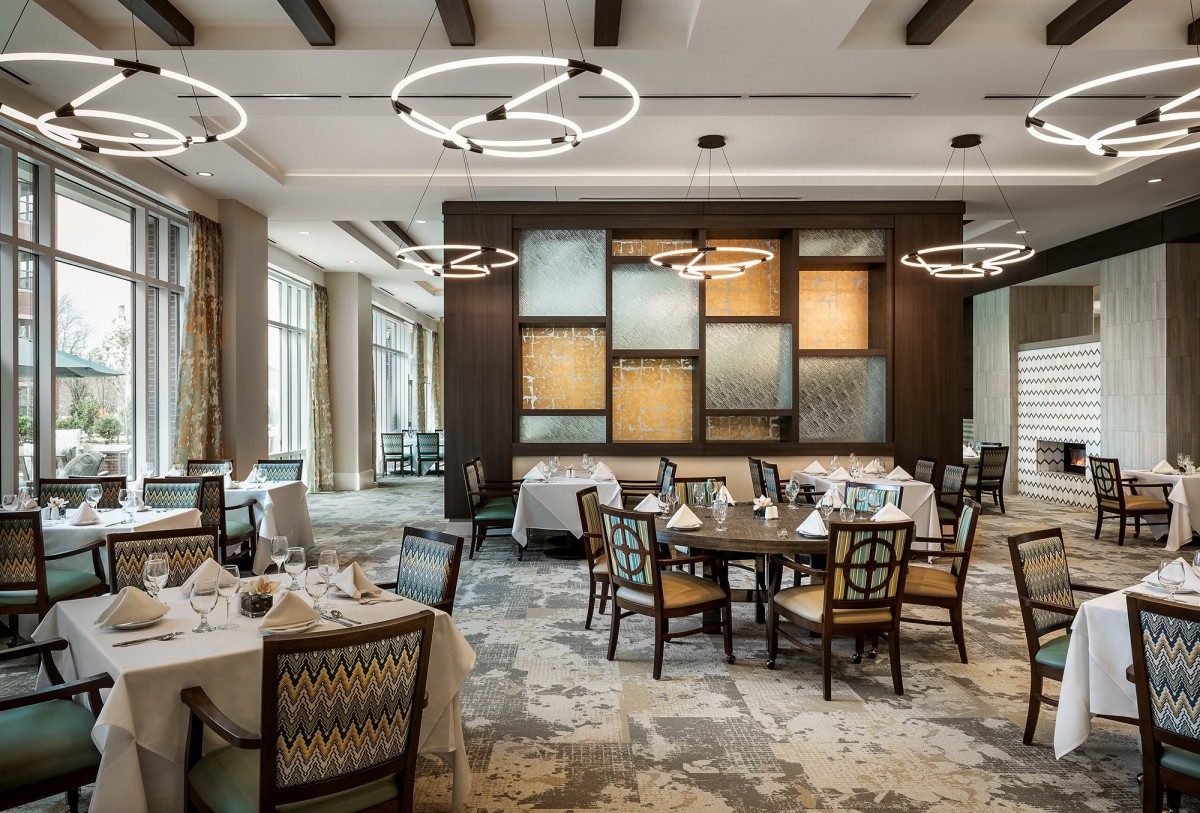 A modern and elegantly designed restaurant dining area with stylish lighting fixtures and neatly set tables.