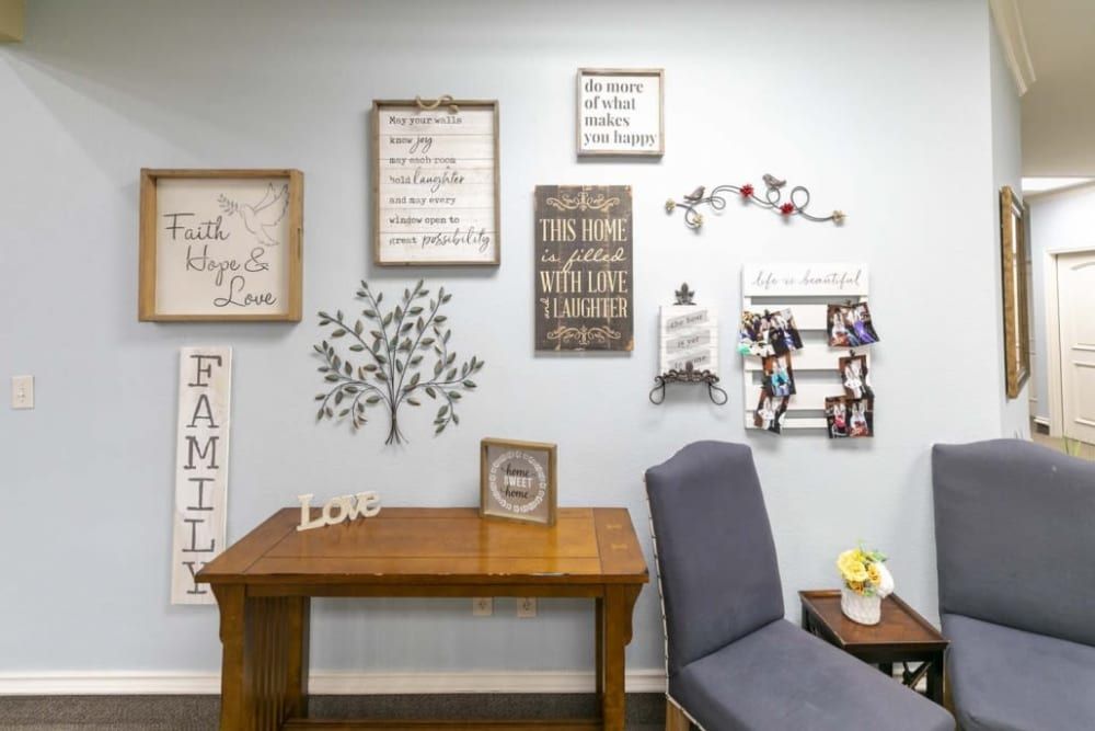 A cozy room corner featuring a wooden desk and chair, with walls decorated with family-themed artwork and quotes.